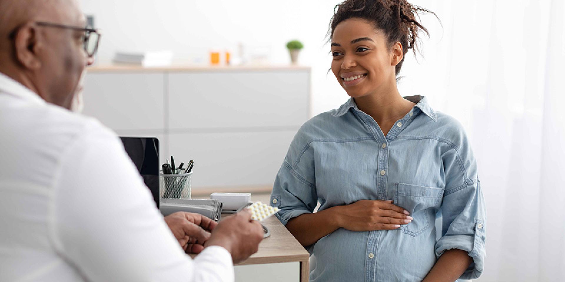 Pregnant person sitting with a doctor discussing medicine